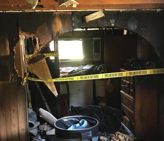 Walls of a home damaged by fire, hole on wall, yellow ribbon awareness in room damaged by fire