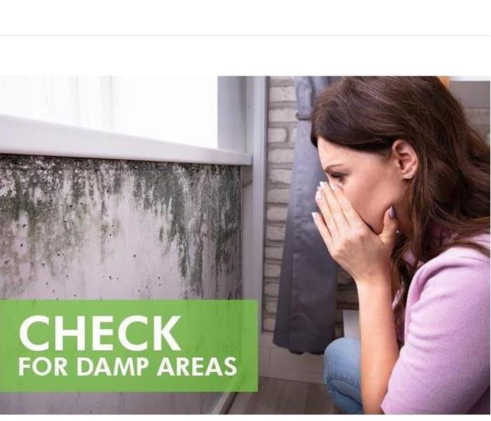 Woman covering her nose while starring at a wall with mold growth