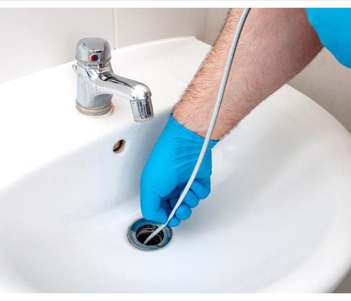 handyman contractor concept with plumber repairing drain with plumbers snake.